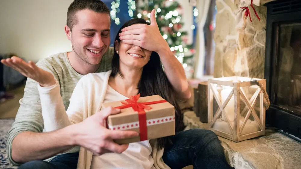 couple opening christmas gift fireplace
